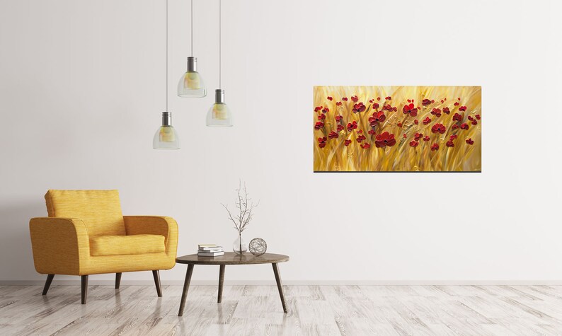 May include: A painting of a field of red poppies against a golden background. The painting is displayed on a white wall in a living room setting with a yellow armchair and a coffee table.