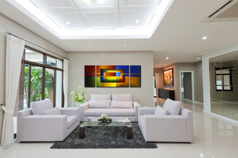 May include: A modern living room with white couches and a coffee table. A large abstract painting with blue, green, yellow, and orange colors hangs on the wall.