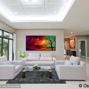 May include: Abstract painting of a colorful landscape with a tree in the foreground. The painting is displayed on a wall in a living room with white furniture.