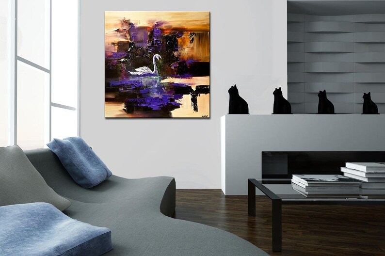 May include: Abstract painting of a white swan in a purple and brown landscape. The painting is hanging on a white wall in a living room with a couch and a coffee table.