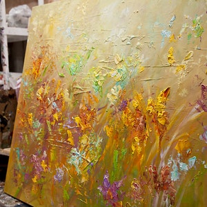 May include: A textured oil painting on canvas depicting a field of flowers in shades of yellow, orange, green, and purple. The flowers are painted with thick brushstrokes, creating a three-dimensional effect.