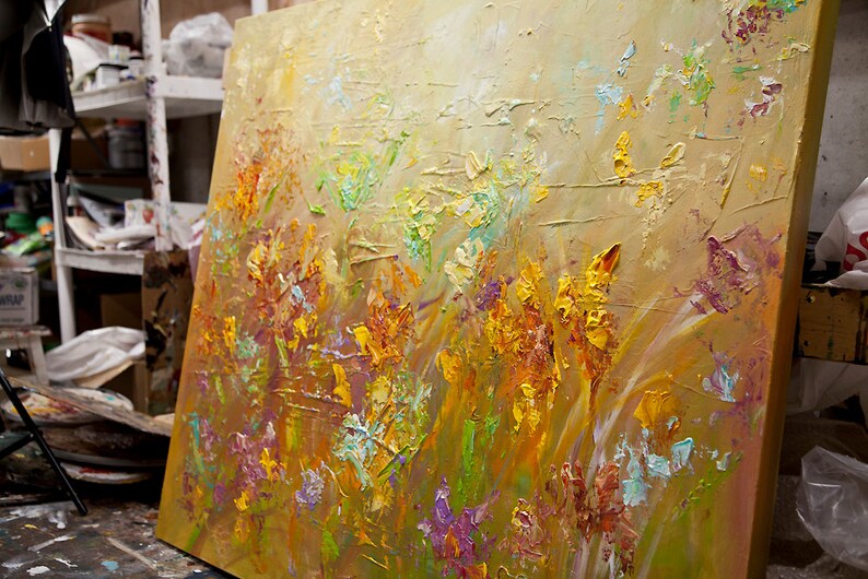 May include: A textured oil painting on canvas depicting a field of flowers in shades of yellow, orange, green, and purple. The flowers are painted with thick brushstrokes, creating a three-dimensional effect.