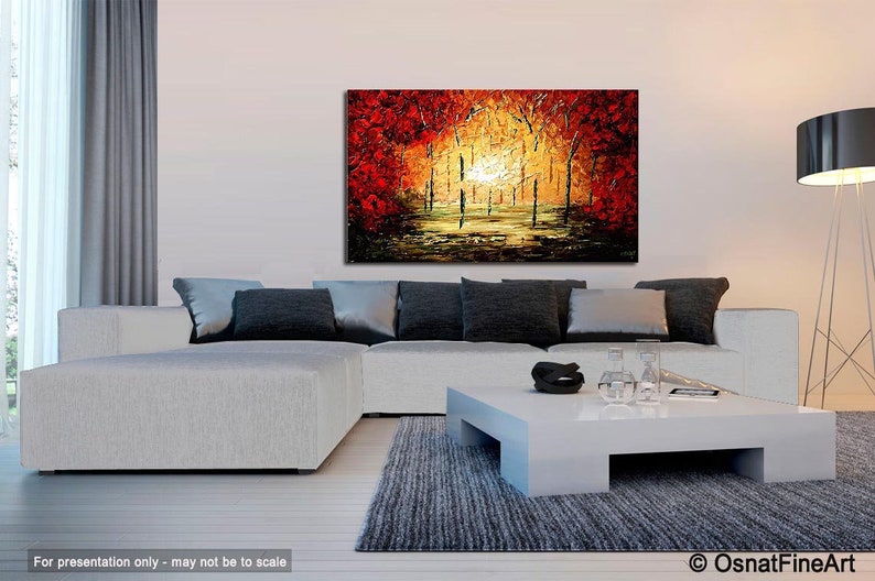 May include: Abstract painting of a forest scene with red, orange, and yellow trees. The painting is on a canvas and is framed. The painting is hanging on a wall in a living room.