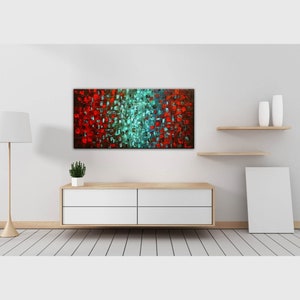 May include: Abstract painting with red, blue, and green squares on a canvas. The painting is hanging on a white wall above a white dresser with four drawers. There are two white vases on a wooden shelf above the dresser.