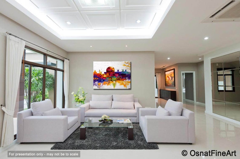 May include: A colorful abstract painting of a cityscape with a white background. The painting is displayed on a wall in a living room with white furniture and a gray rug.