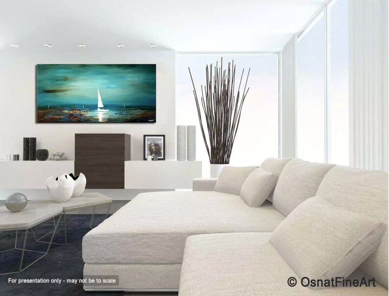 May include: Abstract painting of a sailboat on a teal blue ocean with a white sky. The painting is framed and hanging on a white wall in a living room setting.