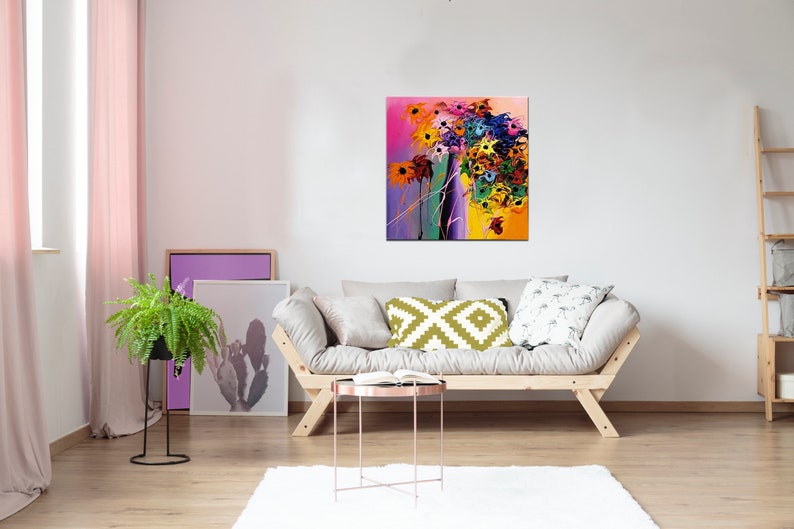 May include: A colorful abstract painting of flowers in a vase. The painting is in a modern style with bold colors and brushstrokes. The painting is hanging on a white wall in a living room setting.