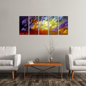 May include: A five-piece abstract art print set featuring a silhouette of a tree against a colorful sunset sky. The print set is displayed on a wall above a coffee table and two armchairs.