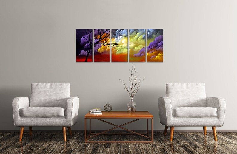 May include: A five-piece abstract art print set featuring a silhouette of a tree against a colorful sunset sky. The print set is displayed on a wall above a coffee table and two armchairs.