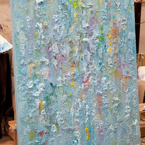 May include: Abstract painting on canvas with a textured surface. The painting is predominantly light blue with accents of yellow, green, pink, and purple.