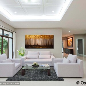 May include: A living room interior design featuring a large abstract painting of a forest scene in gold and brown tones. The painting is hung on a wall above a white sofa and two armchairs. The room has a white ceiling with recessed lighting and a large window with white curtains.
