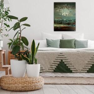 May include: A bedroom with a bed with a green and white patterned blanket, a white headboard, and green pillows. There is a painting above the bed with a white, blue, and brown abstract design. There are three potted plants in the room.