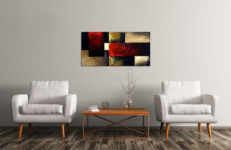 May include: Abstract painting with geometric shapes in shades of black, red, gold, and brown. The painting is hanging on a white wall above a wooden coffee table with two white armchairs.