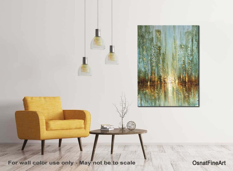 May include: Abstract painting of a city skyline with gold and green hues. The painting is displayed on a white wall in a living room setting with a yellow armchair and a coffee table.