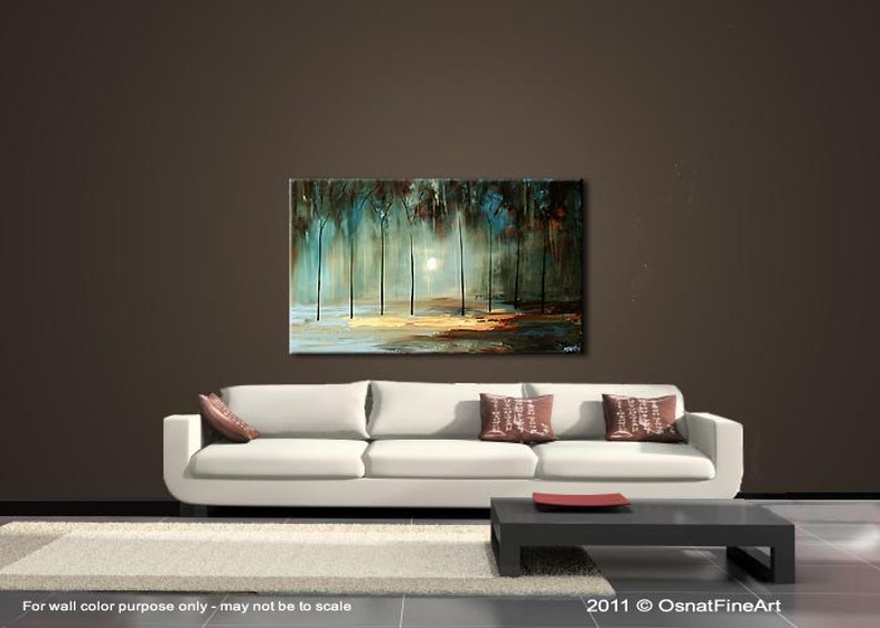 May include: Abstract painting of a forest scene with trees and a bright light in the background. The painting is on a white canvas and is framed in a black frame. The painting is hanging on a wall in a room with a white couch and a coffee table.