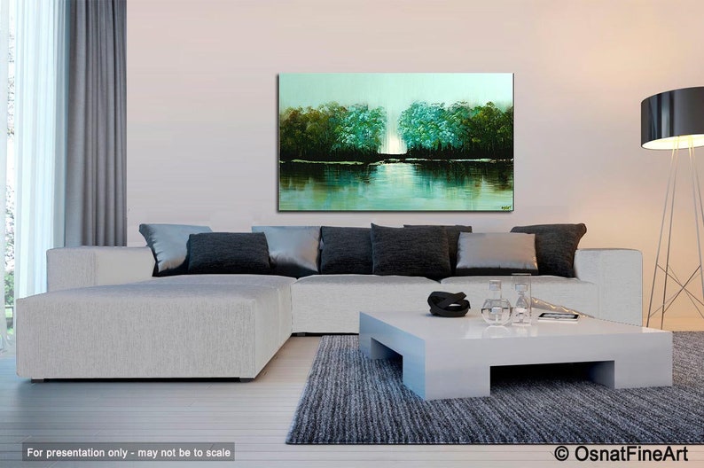 May include: Abstract painting of a lake scene with trees on either side of the water. The water is a light blue-green color and the trees are a dark green. The painting is hanging on a wall in a living room setting.