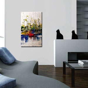May include: Abstract painting with a white background and colorful brushstrokes. The painting features shades of blue, green, yellow, and red. The painting is hanging on a white wall in a modern living room.