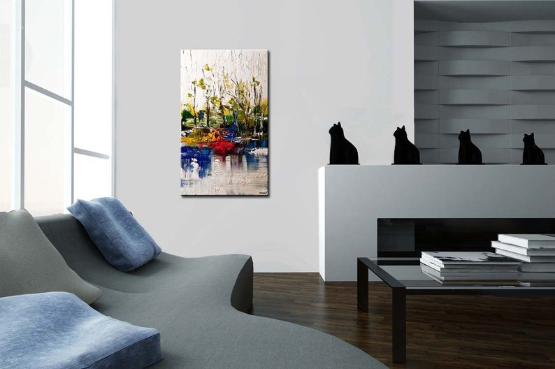 May include: Abstract painting with a white background and colorful brushstrokes. The painting features shades of blue, green, yellow, and red. The painting is hanging on a white wall in a modern living room.