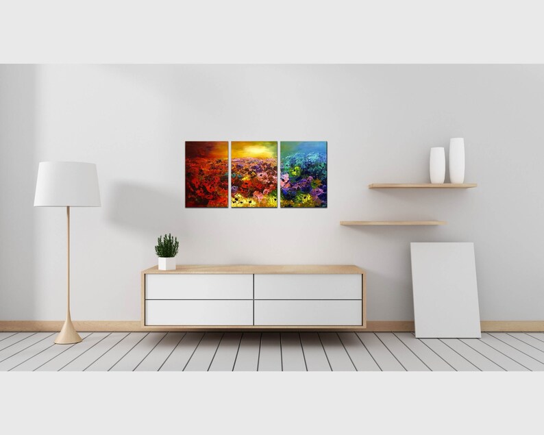 May include: A three-piece abstract art print set featuring a colorful landscape with shades of red, orange, yellow, green, and blue. The prints are framed and displayed on a white wall above a white dresser.