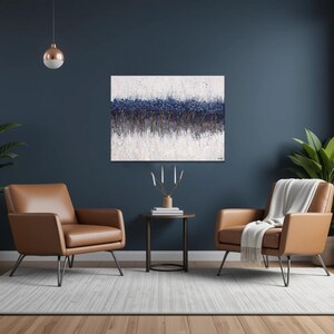May include: A modern living room with two brown leather armchairs, a small round table, and a large abstract painting. The room features large windows, indoor plants, and a neutral rug. The walls are painted a dark blue.