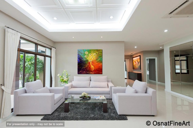 May include: A colorful abstract painting with yellow, green, blue, and orange hues hangs on a wall in a living room. The painting is above a white sofa with two white armchairs and a glass coffee table.