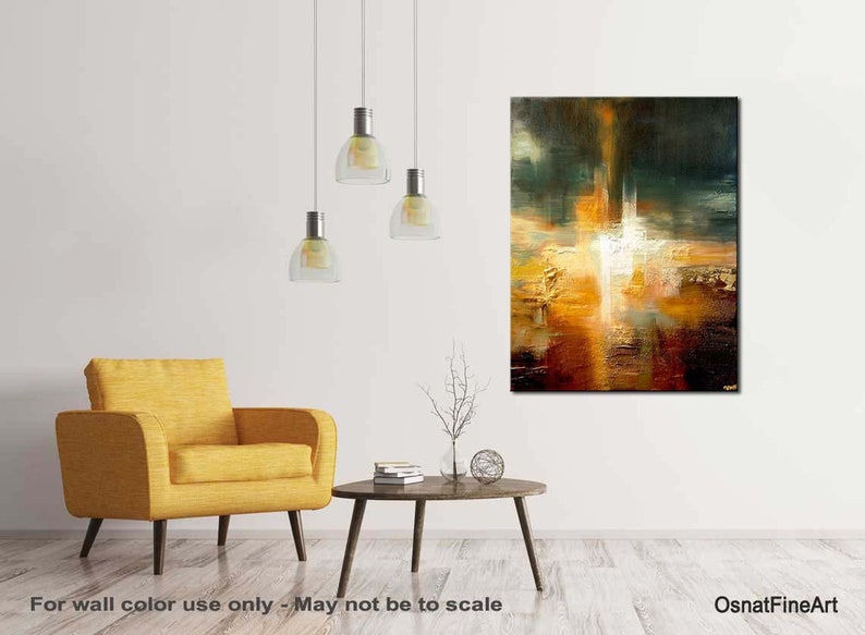 May include: Abstract painting with a white, yellow, orange, and brown colour scheme. The painting is on a canvas and is framed. The painting is hanging on a white wall in a living room setting.