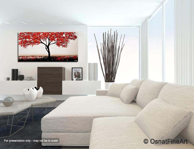 May include: Abstract painting of a red tree with a white trunk against a light gray background. The painting is displayed on a white wall in a living room setting with a white couch and pillows.