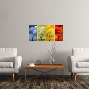 May include: Four abstract paintings of a bare tree against a colorful sky. The paintings are in shades of blue, yellow, orange, and red. The paintings are hung on a white wall above a wooden coffee table and two white armchairs.