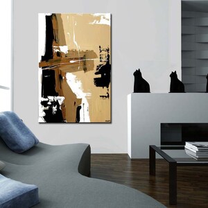 May include: Abstract painting with black, white, and brown brushstrokes on a canvas. The painting is hanging on a white wall in a modern living room.
