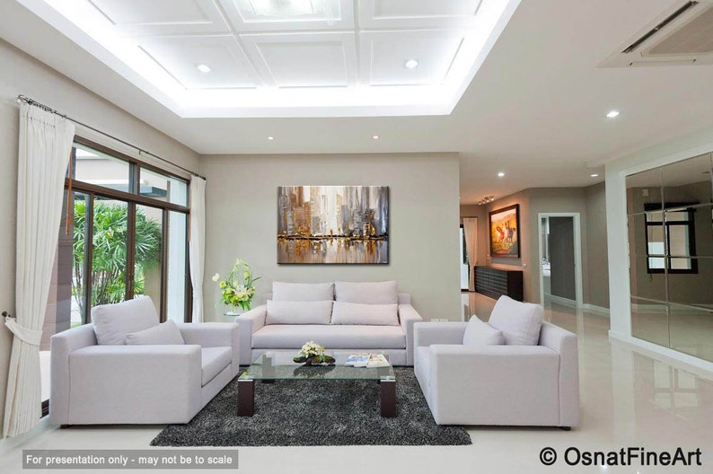 May include: A modern living room with white couches and a coffee table. A large abstract painting of a city skyline in shades of gray, brown, and white hangs on the wall.