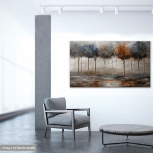 May include: Abstract painting of a forest scene with trees in shades of blue, brown, and gray. The trees are silhouetted against a misty background. The painting is displayed on a wall in a modern living room setting.