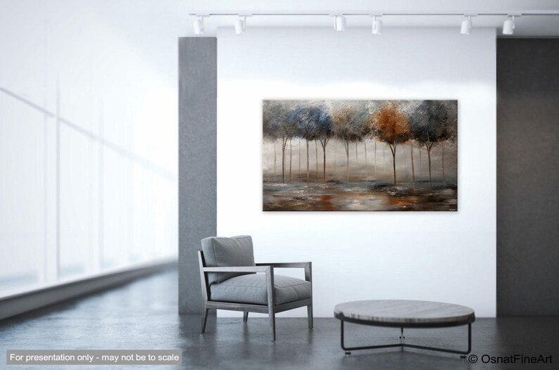 May include: Abstract painting of a forest scene with trees in shades of blue, brown, and gray. The trees are silhouetted against a misty background. The painting is displayed on a wall in a modern living room setting.