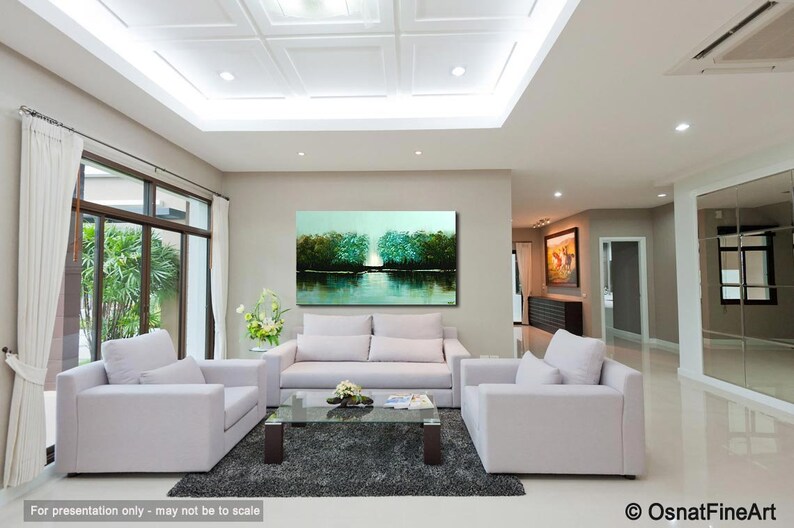 May include: A living room interior design with a large abstract landscape painting in teal, green, and blue hues hanging on the wall above a white sofa. The painting depicts a lake with trees reflected in the water. The room has a white tiled floor and white furniture.