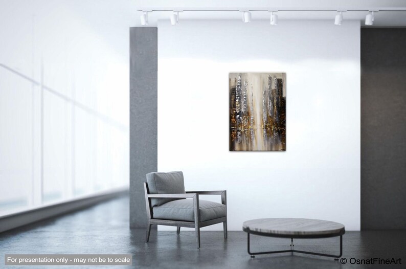 May include: Abstract painting of a city skyline in shades of gray, brown, and gold. The painting is displayed on a white wall in a modern living room setting.