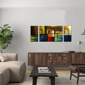 May include: A three-piece abstract art print set featuring geometric shapes in shades of blue, green, red, yellow, and brown. The prints are framed and hung on a white wall above a brown wooden cabinet.
