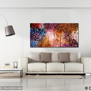 May include: Abstract painting of a forest with colorful trees in shades of purple, blue, orange, and red. The trees are silhouetted against a light background. The painting is displayed on a white wall in a living room setting.