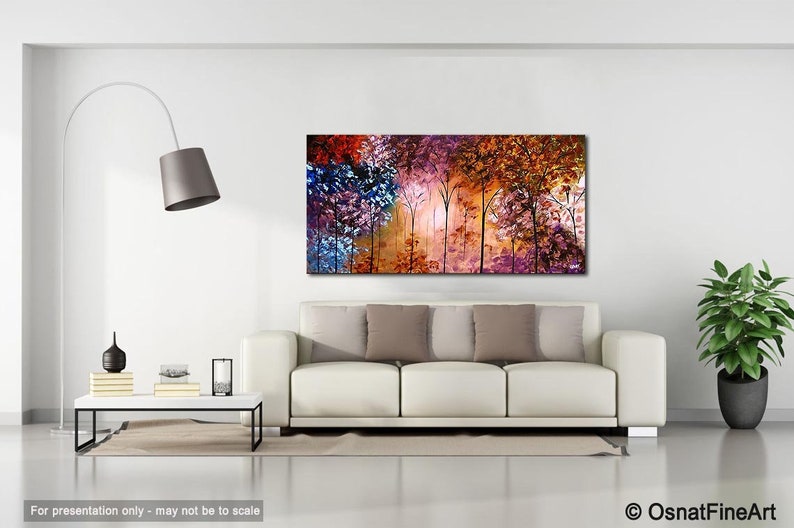 May include: Abstract painting of a forest with colorful trees in shades of purple, blue, orange, and red. The trees are silhouetted against a light background. The painting is displayed on a white wall in a living room setting.