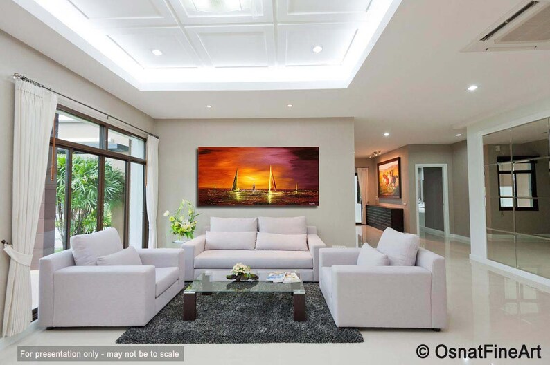 May include: A living room interior with a white couch and two white armchairs. A large abstract painting of a sunset with sailboats hangs on the wall above the couch. The painting is in shades of orange, yellow, and purple.