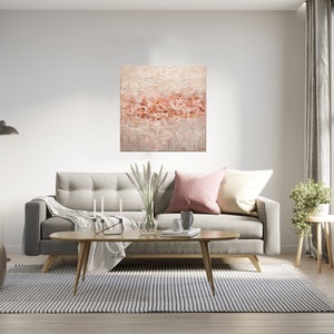 May include: A living room interior with a gray sofa, a coffee table, a rug, a floor lamp, a potted plant, and a painting on the wall. The painting is abstract and features a pink and white color scheme.