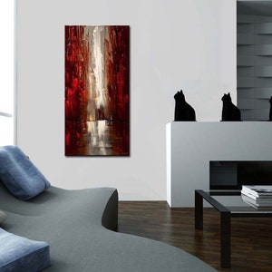 May include: Abstract painting with red, white, and gray colors. The painting depicts a city scene with tall buildings and a reflective surface. The painting is hanging on a white wall in a living room setting.