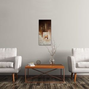 May include: Two white armchairs with wooden legs face each other across a wooden coffee table with a metal frame. A brown and white abstract painting hangs on the wall behind the table.