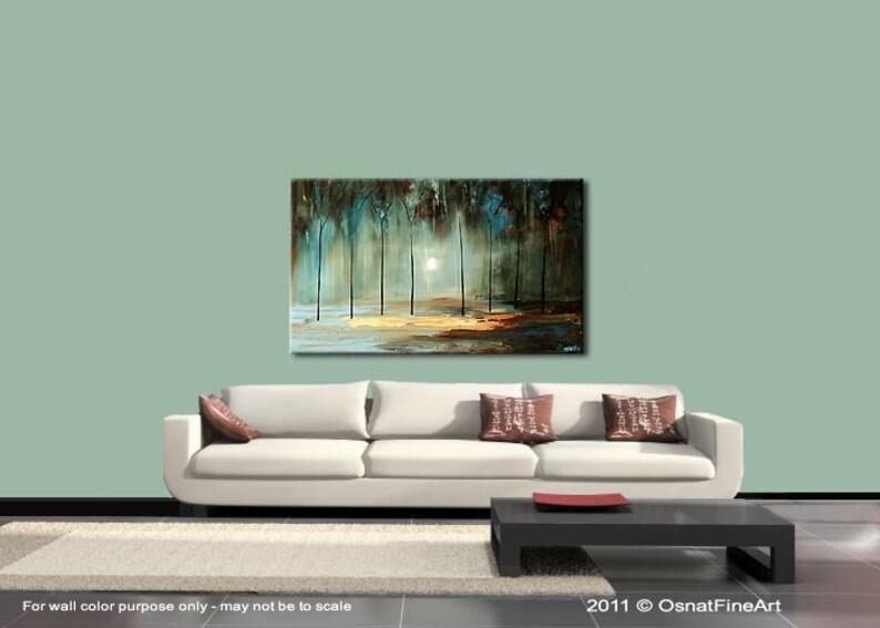 May include: Abstract painting of a forest scene with trees in shades of blue, green, and brown. The trees are silhouetted against a white sky with a bright light shining through the branches. The painting is displayed on a white wall above a white couch with brown pillows.