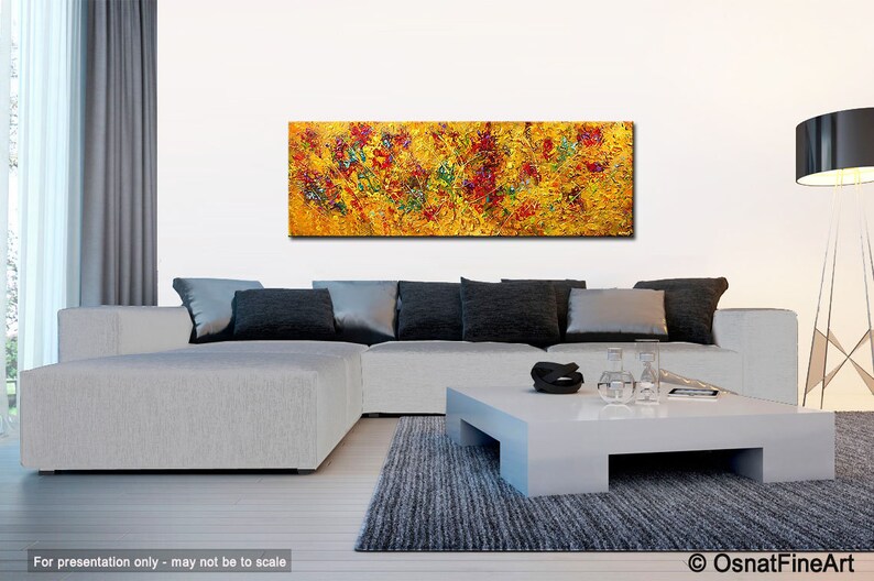 May include: Abstract painting with a yellow background and red, green, and blue accents. The painting is displayed on a white wall above a gray sectional sofa and a white coffee table.