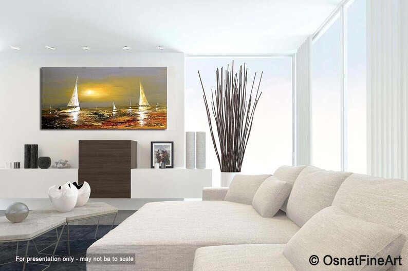 May include: A painting of sailboats on a body of water at sunset. The sky is a soft purple and orange, and the water is a deep blue. The sailboats are white and have a golden glow. The painting is framed and hanging on a white wall in a modern living room.