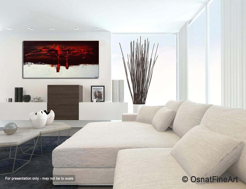 May include: Abstract painting in red, white, and black colors. The painting is hanging on a white wall in a modern living room with a white couch and a black and brown coffee table.