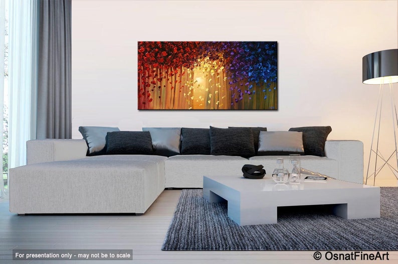 May include: Abstract painting with a colorful, textured design. The painting features a mix of red, orange, yellow, blue, and purple hues. The painting is displayed on a wall in a living room setting.