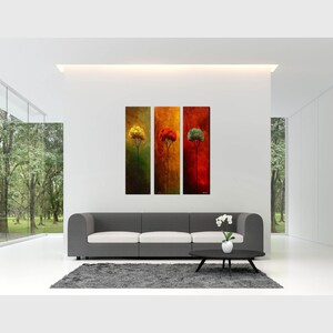 May include: Three abstract paintings of trees in a modern living room with a gray sofa and a white orchid plant on a black coffee table.