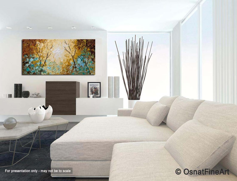 May include: A large abstract painting with a brown, yellow, and blue color scheme. The painting depicts a forest scene with trees and leaves. The painting is hanging on a white wall in a modern living room.