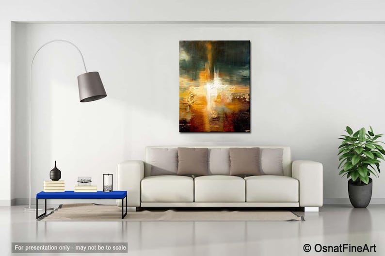 May include: Abstract painting with a white light in the centre, surrounded by shades of brown, orange, and yellow. The painting is hanging on a white wall above a white sofa with brown cushions.