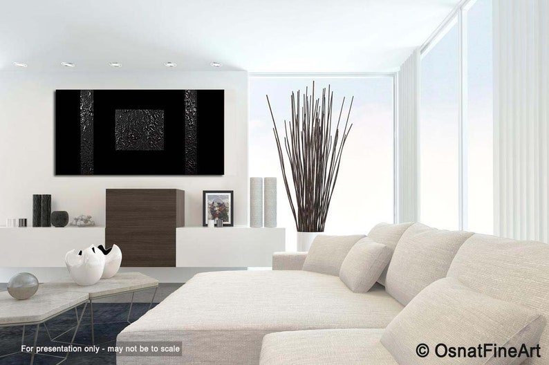 May include: Black and white abstract painting with a textured surface. The painting is hanging on a white wall in a modern living room with a white couch and a vase of brown branches.